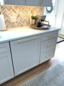 Close up view of the cabinets in a newly renovated kitchen, featuring white paint and gold accents